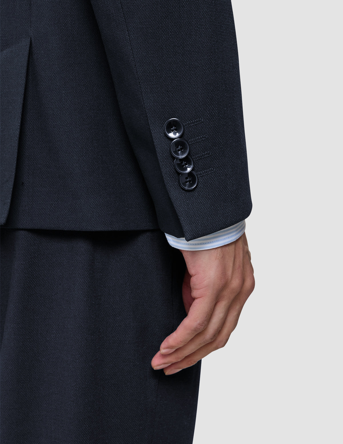 Nærbillede af et ærme fra en Motion Blazer Slim i farven Midnight Blue med fire manchetknapper og en stribet skjorte, der kan ses ved håndleddet.