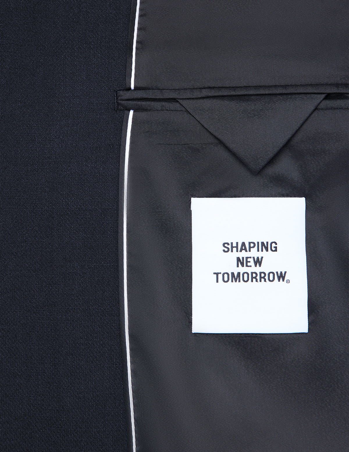 Indersiden af en mørkeblå Motion Blazer Slim Midnight Blue med et hvidt mærke, hvor der står SHAPING NEW TOMORROW.