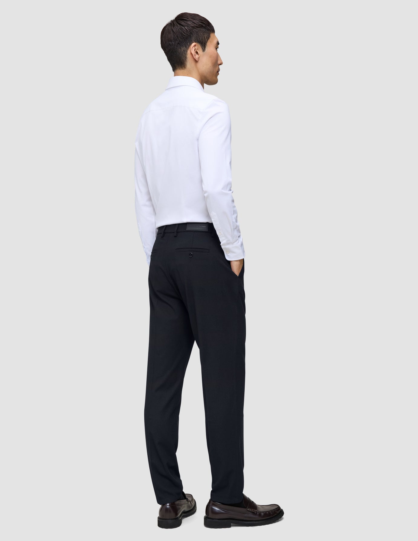 Bagfra-billede af en mand i en hvid skjorte med knapper og et par Midnight Blue Motion-bukser i Regular-pasform med 360°-stretch.