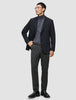 En mand i en sort blazer, en grå rullekravebluse og et par Motion Suit-bukser i farven Regular Pepper Grey.