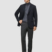 En mand i en sort blazer, en grå rullekravebluse og et par Motion Suit-bukser i farven Regular Pepper Grey.