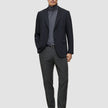 En mand iført en sort blazer, en grå rullekravebluse, Motion Suit-bukser i Regular-pasform i farven Pepper Grey og sorte loafers.