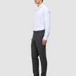 En mand i en hvid skjorte og Motion Suit-bukser i Regular Pepper Grey står set i profil og er indbegrebet af det rene danske design.