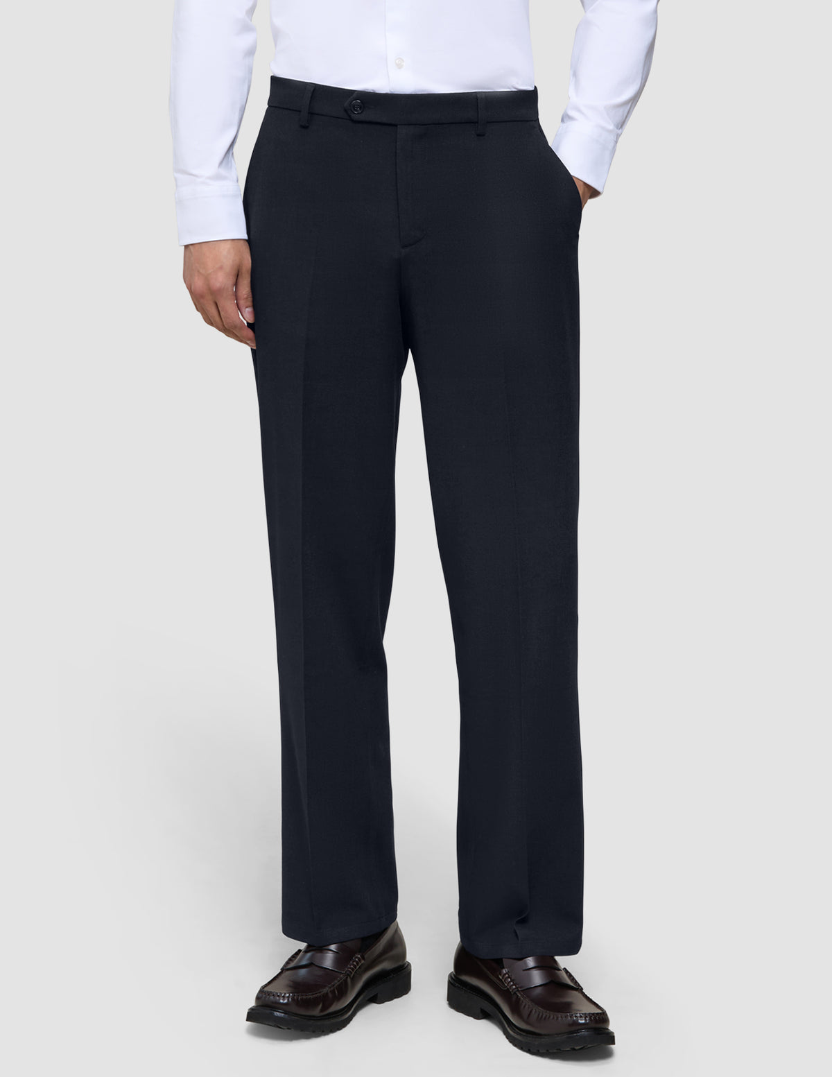 Motion Suit-bukser i afslappet pasform i midnatsblå med 360°-stretch, kombineret med en hvid skjorte og mørke loafers.