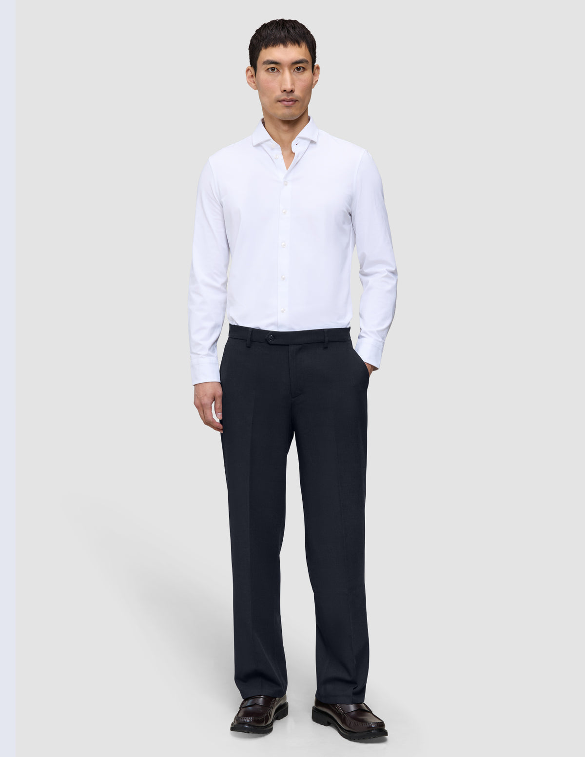 En mand i en hvid skjorte med knapper og et par Motion Suit-bukser i afslappet pasform i midnatsblå med 360°-stretch.