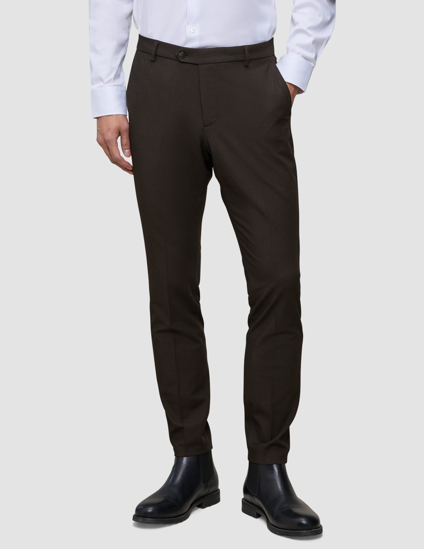 Brune Motion-bukser i slim fit i farven Slim Cognac, kombineret med en hvid skjorte med knapper og sorte støvler.