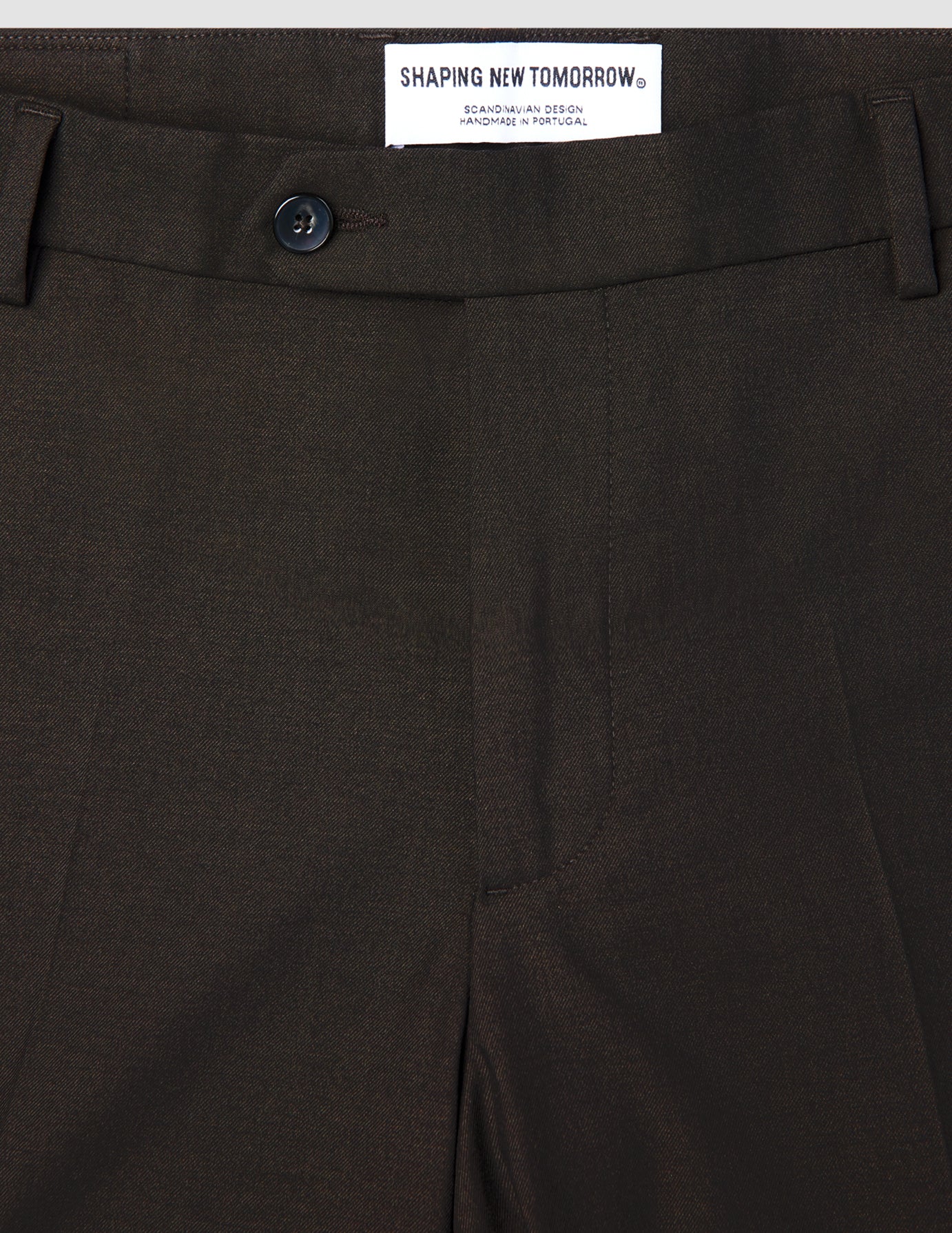 Nærbillede af taljen og knappen foran på de mørkebrune Motion Suit Pants Slim Cognac.