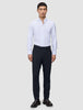 En mand iført en hvid skjorte med knapper, Motion Suit-bukser i slim fit i midnatsblå og mørkebrune loafers.