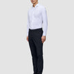 En mand i en hvid skjorte med knapper og et par Motion Suit-bukser i slim fit i midnatsblå, der fremhæver klassisk dansk design.