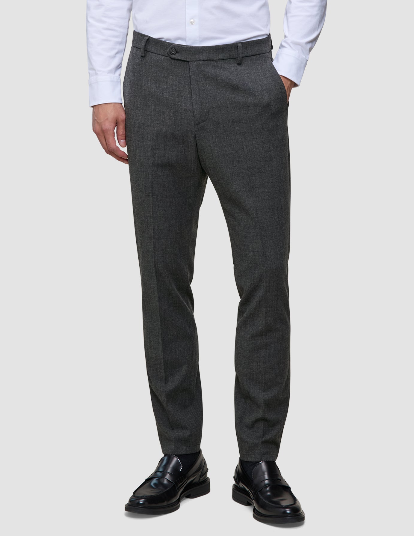 Motion Suit-bukser i Slim-pasform i farven Pepper Grey i mørkegrå med 360°-stretch, kombineret med en hvid skjorte med knapper og sorte loafers.