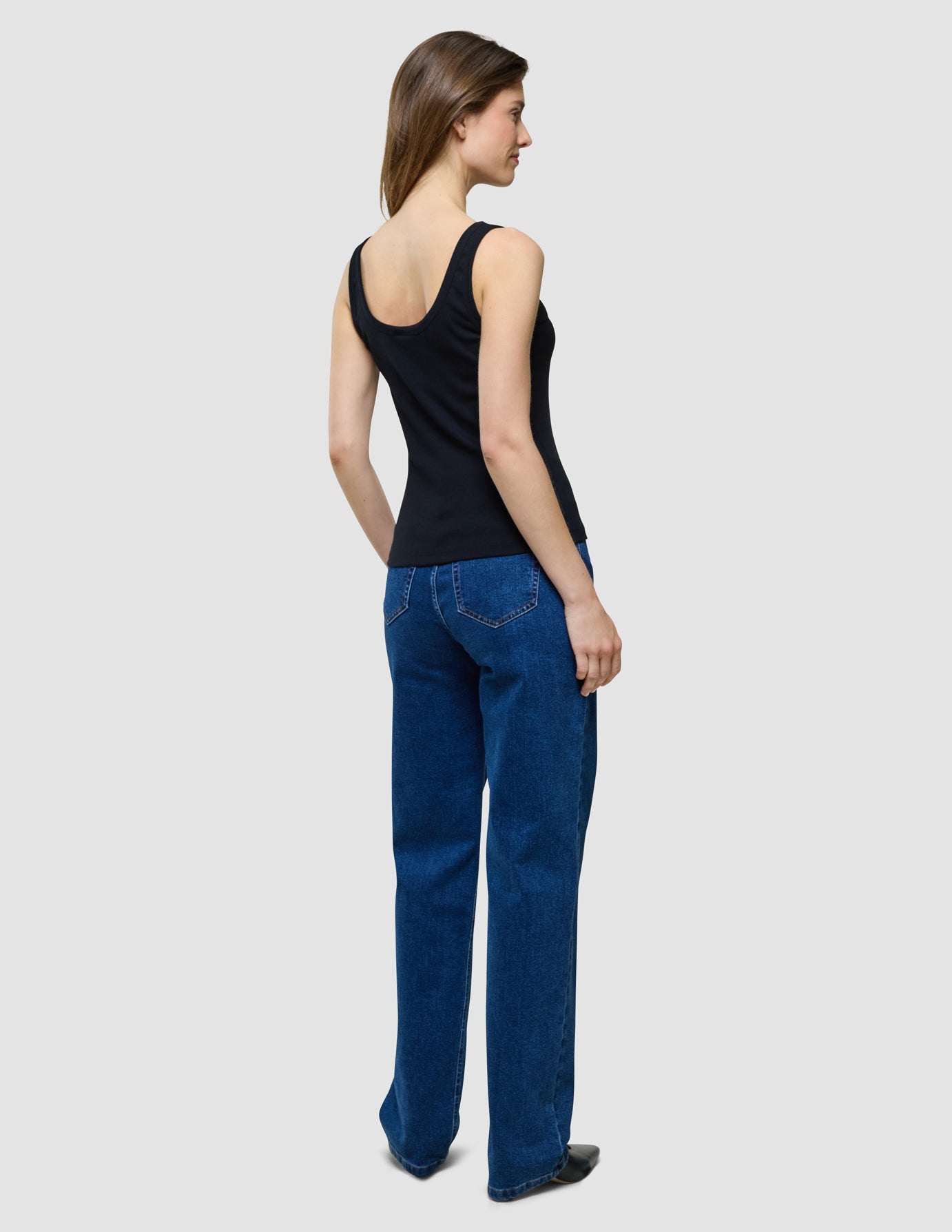 Rib Top i Black, helfigur set bagfra af kvinde i sort ærmeløs top og blå jeans.