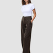 En kvinde iført en hvid T-shirt og et par Serene Pants Wide Walnut Herringbone-bukser med høj talje og brede ben i nålestribet mønster.
