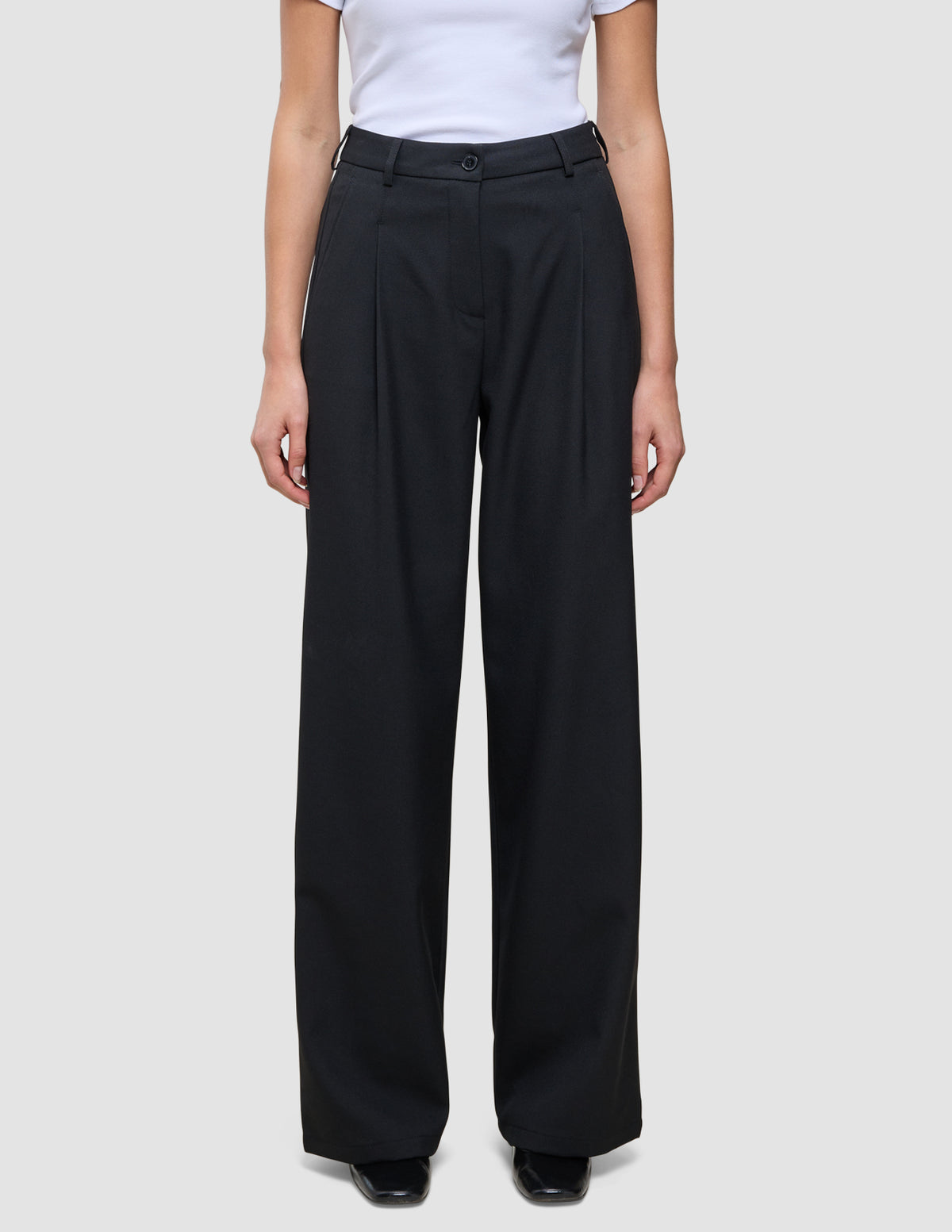 Person iført en hvid T-shirt og et par Serene Pants Wide Black med læg foran.