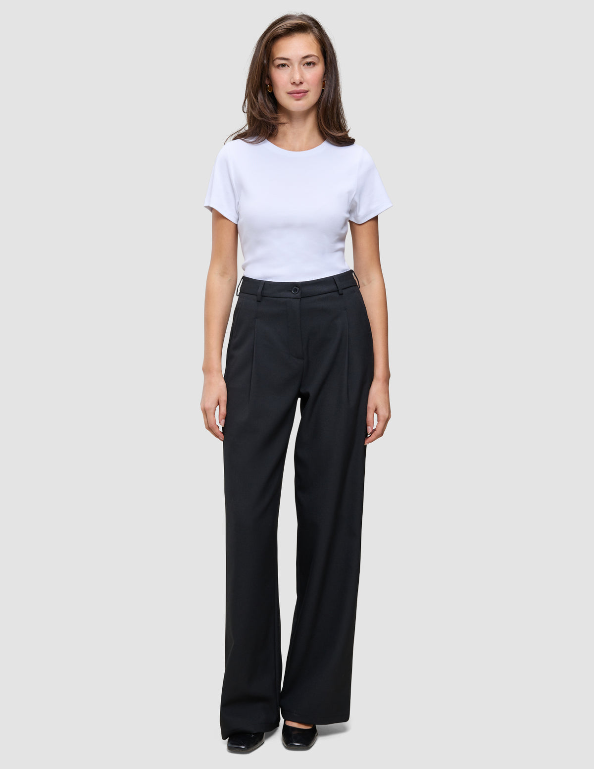 En kvinde iført en hvid T-shirt og et par Serene Pants Wide Black med brede ben.