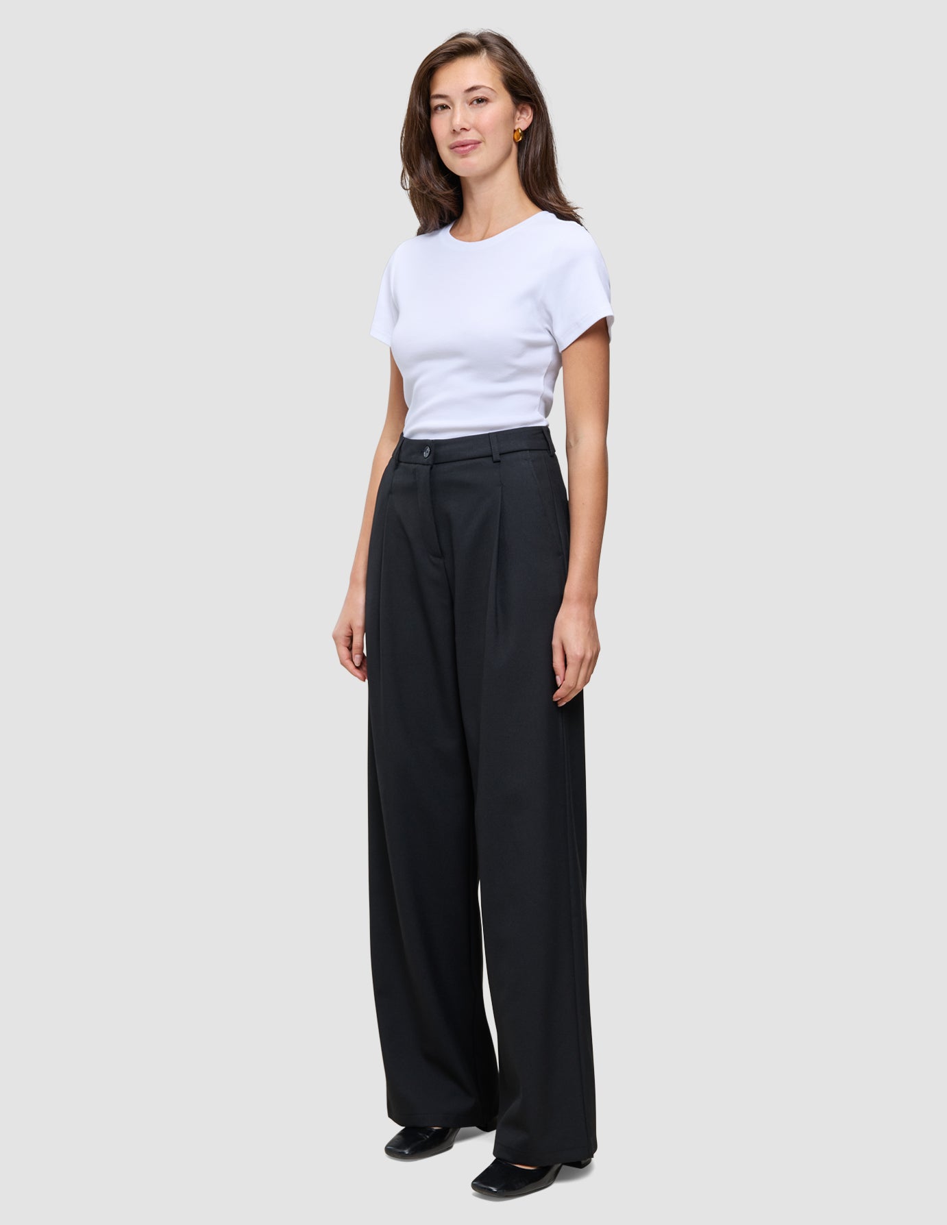 Kvinde iført en hvid T-shirt og sorte Serene Pants Wide Black med bredt ben og høj talje.