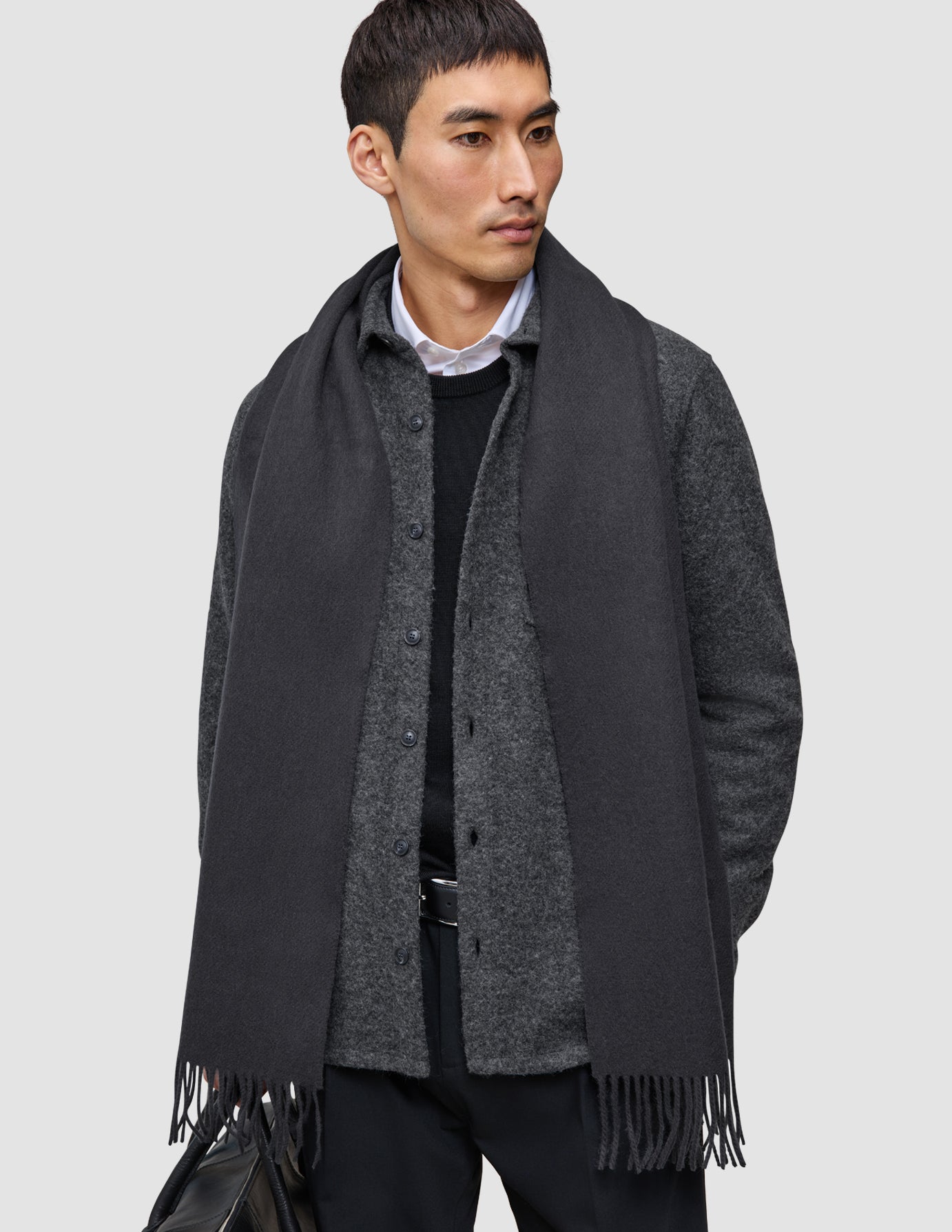 En mand har en Layers that work-trøje i merinould på over en grå skjorte med knapper og et antracitgråt tørklæde.
