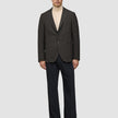En person iført en mørkebrun, slim-fit Timeless Wool Blazer med tern over en beige rullekravebluse og mørke bukser.