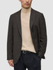 En mand har en mørkebrun, slim-fit Timeless-uldblazer med tern på over en beige rullekravesweater og sorte bukser.
