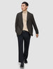 En mand har en mørkebrun, slim-fit Timeless-uldsblazer med tern på over en beige rullekravebluse og mørke bukser.