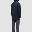 En person set bagfra, iført en sort Utility Jacket, grå bukser og sorte sko.