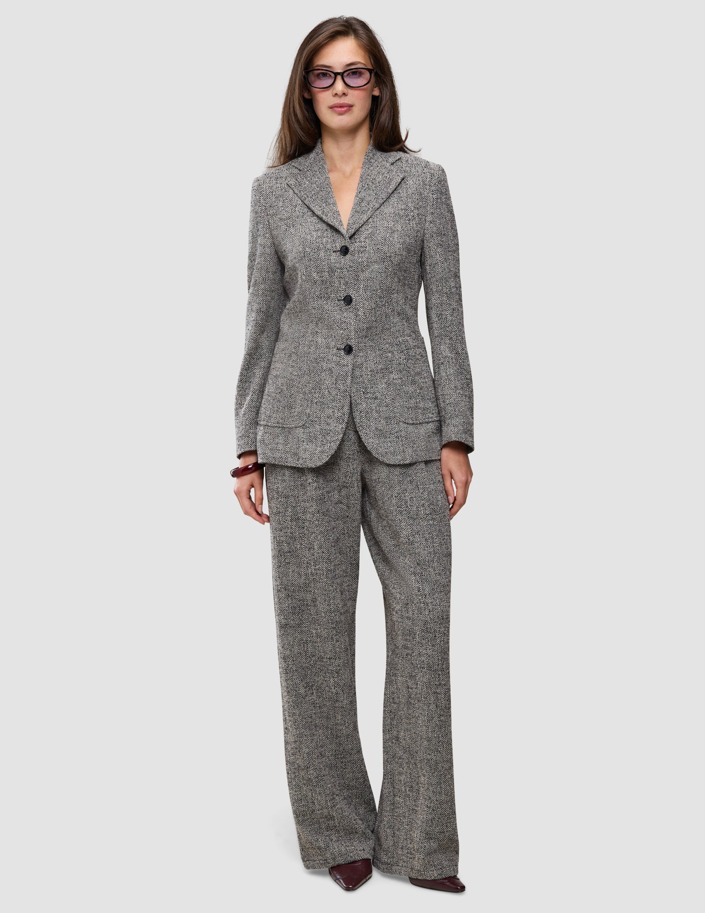 En model bærer en grå blazer i fiskebensmønster og de tilhørende Women Ashryn Pants Wide Domino Herringbone i klassisk dansk design.