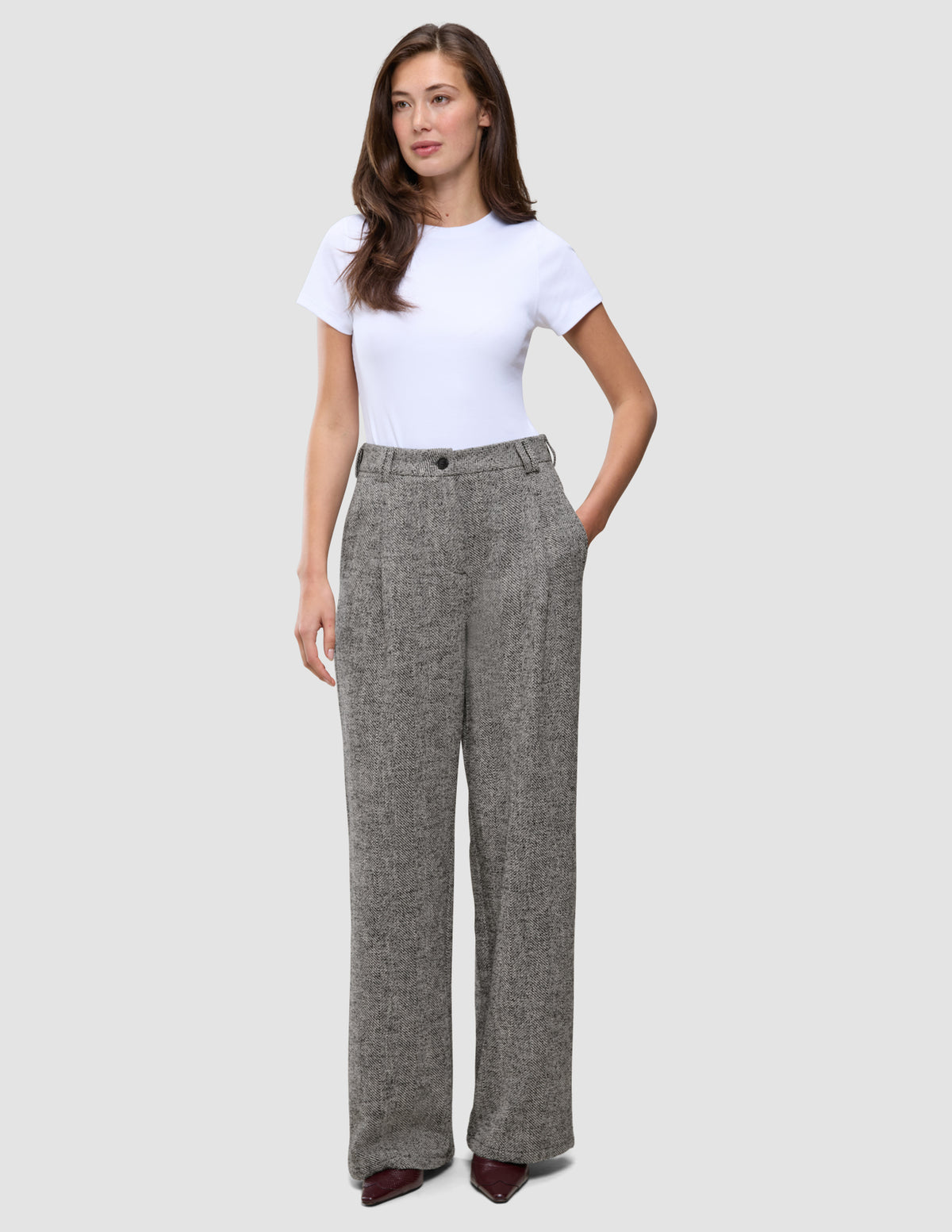 Kvinde iført en hvid T-shirt og grå Women Ashryn Pants Wide Domino Herringbone med et struktureret bouclé-mønster.