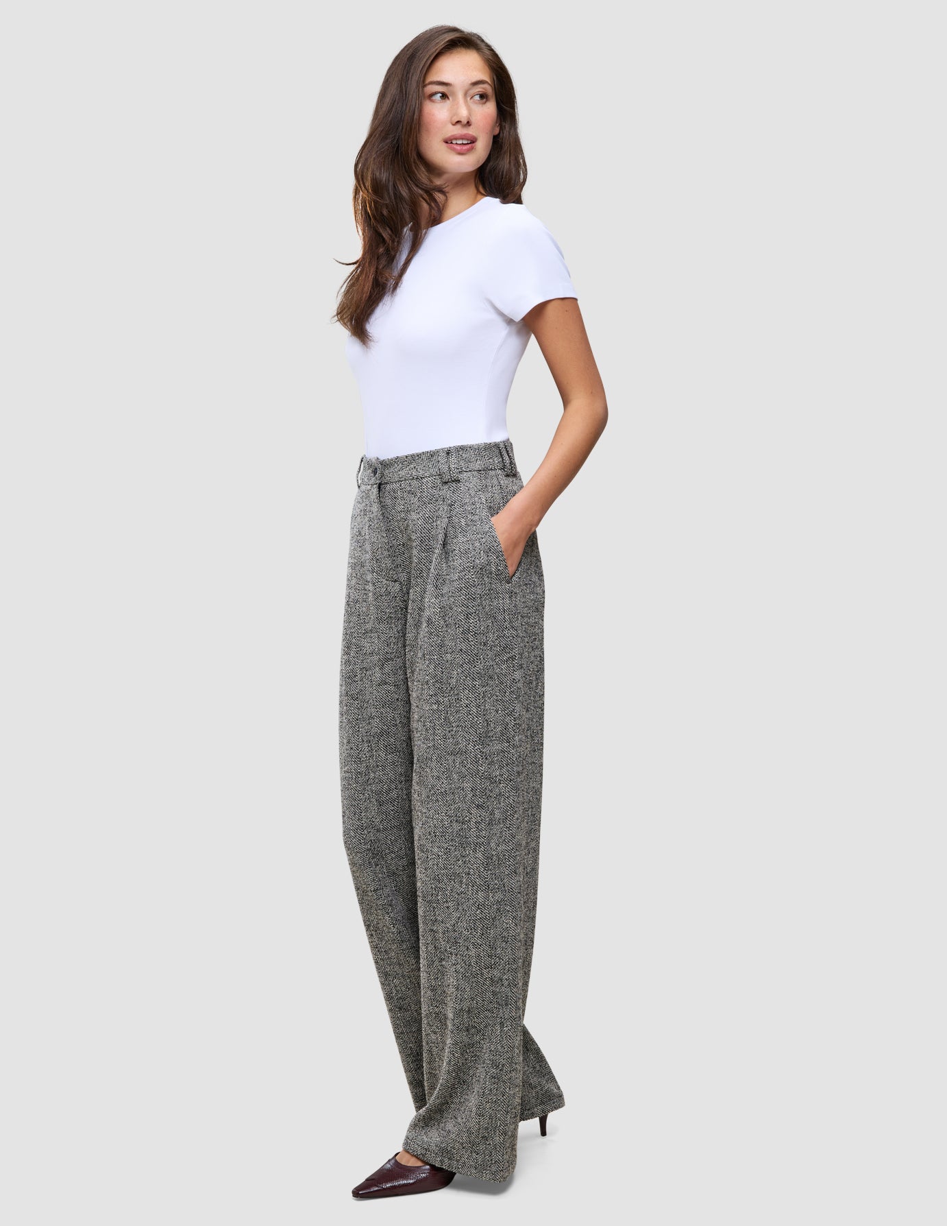 En kvinde i en hvid T-shirt og Women Ashryn Pants Wide Domino Herringbone-bukser i et klassisk dansk design.