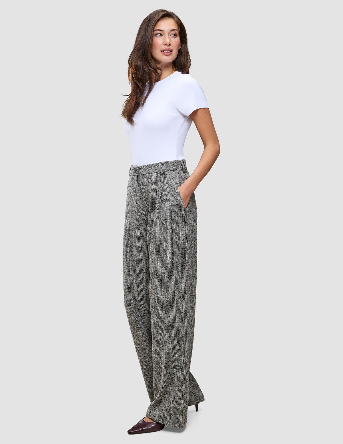 En kvinde i en hvid T-shirt og Women Ashryn Pants Wide Domino Herringbone-bukser i et klassisk dansk design.