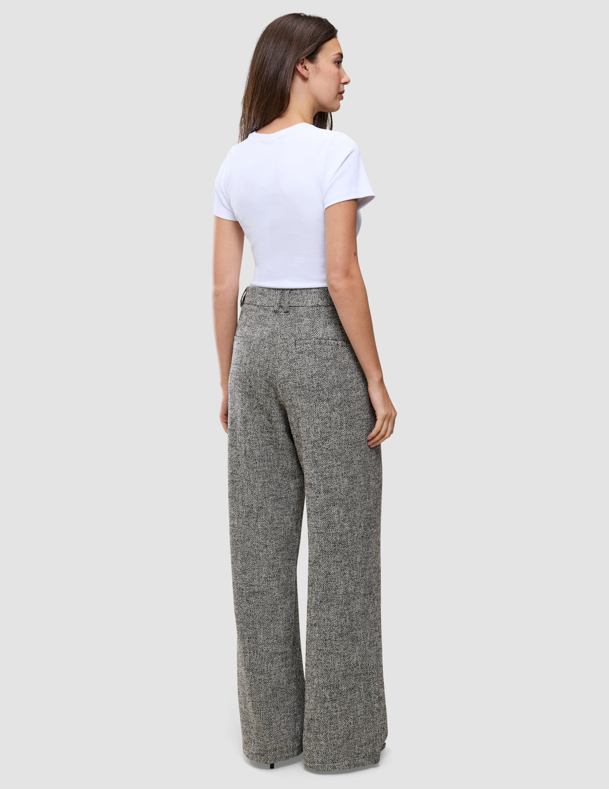 En kvinde set bagfra, iført en hvid T-shirt og grå Women Ashryn Pants Wide Domino Herringbone.