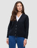 En kvinde iført en sort, tyk, blød uldstrikket cardigan fra serien Women over en hvid skjorte og blå jeans.