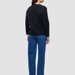 Set bagfra har personen en sort, tyk, blød uldstrikket cardigan til kvinder på over en hvid skjorte og blå jeans.