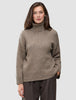 En kvinde iført en Women Chunky Soft Wool Knit Turtleneck Taupe Melange – en grovstrikket merinoullstrøje i taupe-melange.
