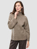 En kvinde har en Women Chunky Soft Wool Knit Turtleneck Taupe Melange på, en tyk, taupefarvet rullekravesweater i merinould.