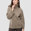 En kvinde har en Women Chunky Soft Wool Knit Turtleneck Taupe Melange på, en tyk, taupefarvet rullekravesweater i merinould.