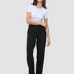 Kvinde i en hvid T-shirt, Women GO2-bukser i lige snit i sort og mørke loafers.