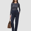 En kvinde i en grå langærmet bluse har Women GO2 Pants Straight Blue Nights på og holder en brun håndtaske.