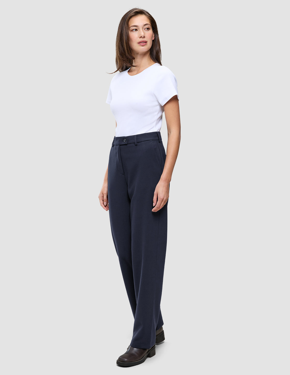 En kvinde iført en hvid T-shirt og et par Women GO2-bukser med høj talje i modellen Straight i farven Blue Nights.