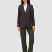 En kvinde har en brun blazer med tynde striber på over en hvid T-shirt og et par Women GO2-bukser i model Straight i farven Dusty Olive.