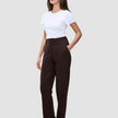 En kvinde i en hvid T-shirt og et par Women GO2 Pants Straight Mocha med hånden i lommen.