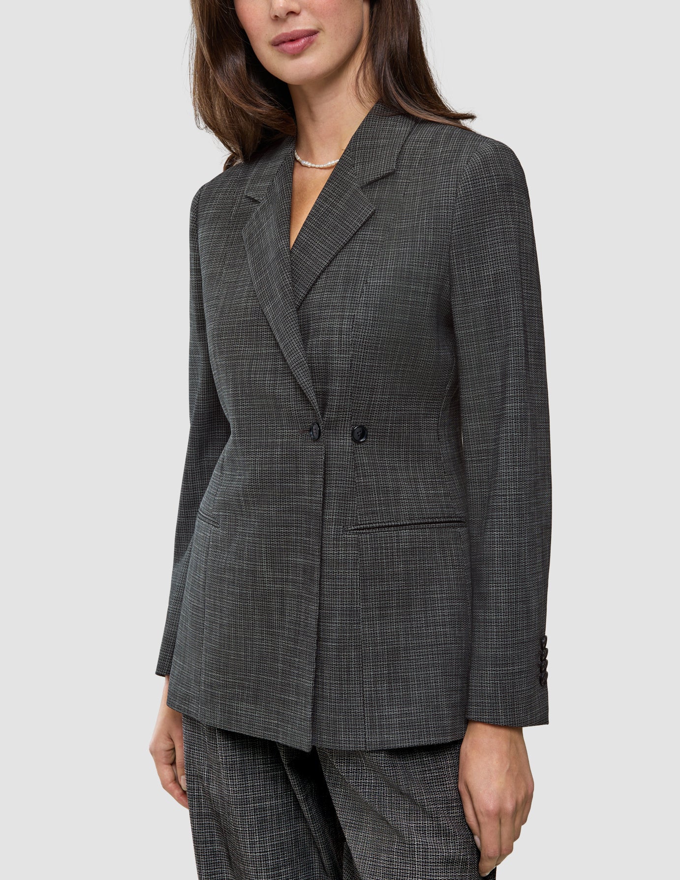 En kvinde iført en Women Nara Blazer Fitted Black Check, en sort-hvid ternet blazer med dobbeltknapning.