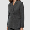 En kvinde iført en Women Nara Blazer Fitted Black Check, en sort-hvid ternet blazer med dobbeltknapning.