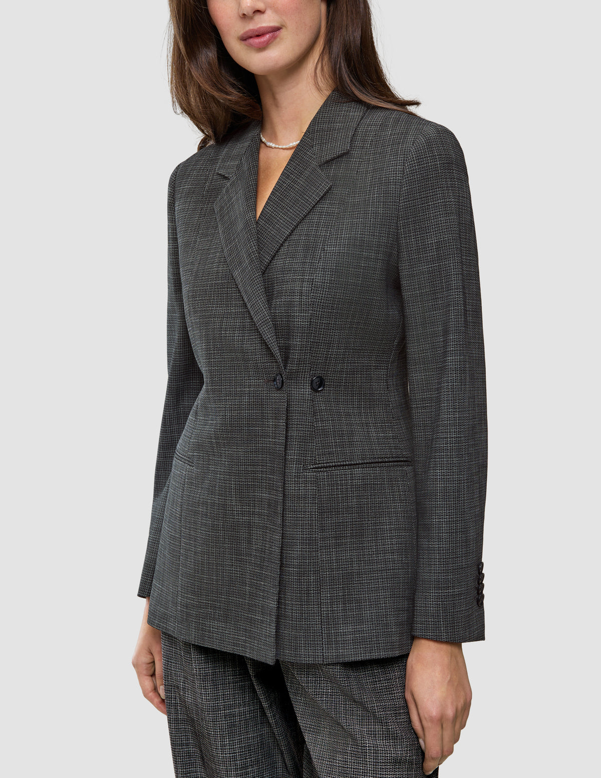 En kvinde iført en Women Nara Blazer Fitted Black Check, en sort-hvid ternet blazer med dobbeltknapning.