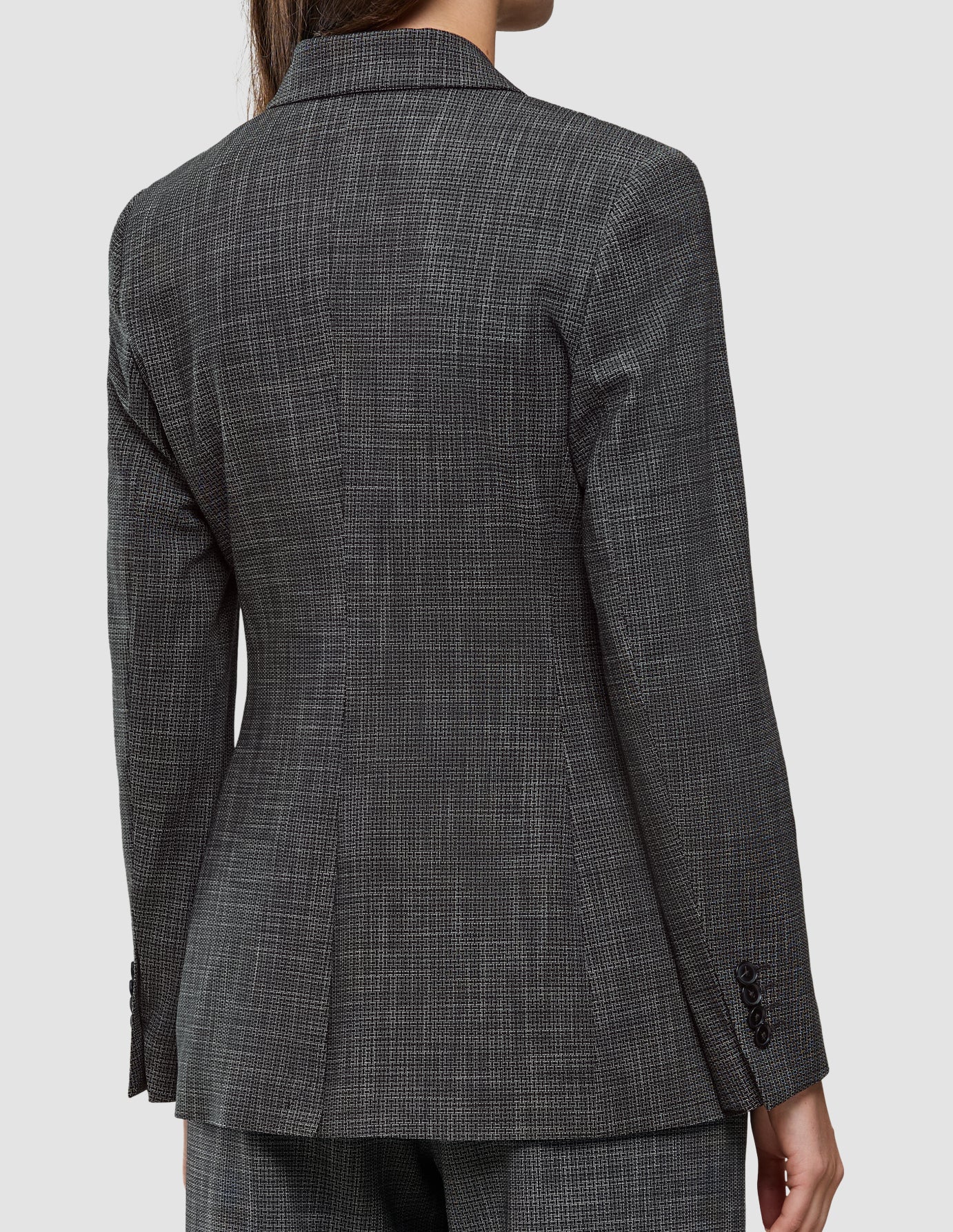 Bagfra-billede af en person, der bærer en Women Nara Blazer Fitted Black Check med et figurbetonende sort-hvidt ternet mønster.