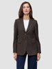 En kvinde iført en Women Serene Blazer Regular Walnut Herringbone over en hvid T-shirt og blå jeans.