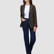En person, der har en brun Women Serene Blazer Regular Walnut Herringbone på over en hvid T-shirt og blå jeans.