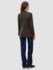 Bagfra-billede af en person iført en Women Serene Blazer Regular Walnut Herringbone, mørkeblå jeans og brune sko.