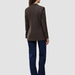 Bagfra-billede af en person iført en Women Serene Blazer Regular Walnut Herringbone, mørkeblå jeans og brune sko.