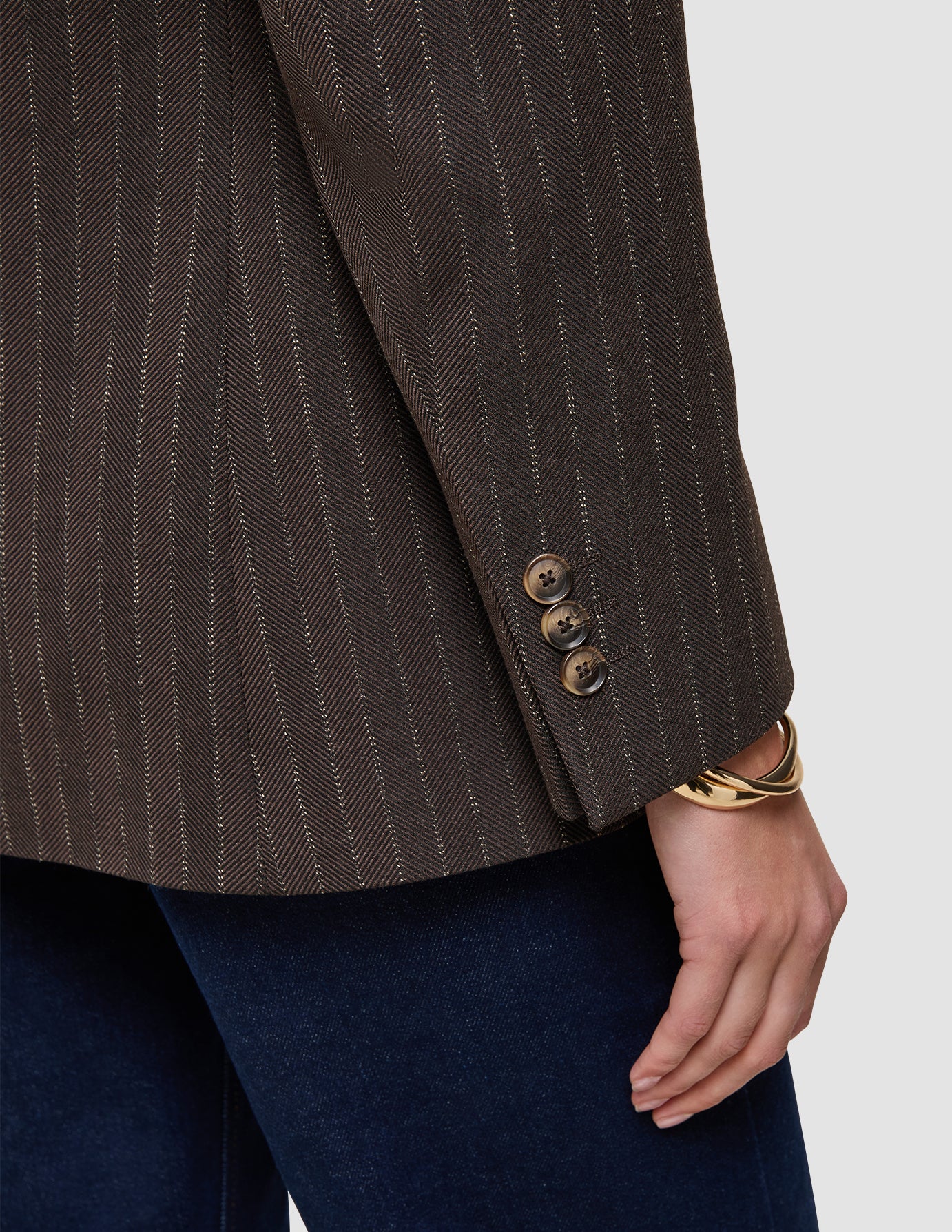 Nærbillede af en Women Serene-blazer i almindelig pasform med ærmer i valnød-sildbenmønster, fremstillet af brun uld i sildbenmønster med tre knapper ved manchetterne.