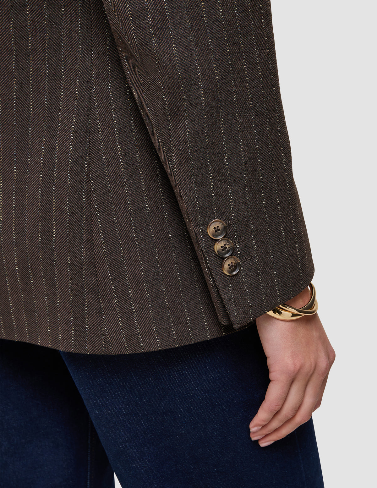 Nærbillede af en Women Serene-blazer i almindelig pasform med ærmer i valnød-sildbenmønster, fremstillet af brun uld i sildbenmønster med tre knapper ved manchetterne.