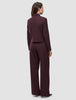 En kvinde set bagfra har den korte jakke Women Serene Short Jacket Berry Pinstripe på sammen med et par matchende bukser med brede ben.